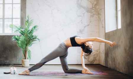 woman in gray leggings and black sports bra doing yoga on yoga mat